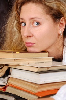 Woman resting chin on stack of books