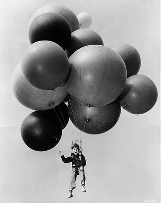 child flying away with balloons
