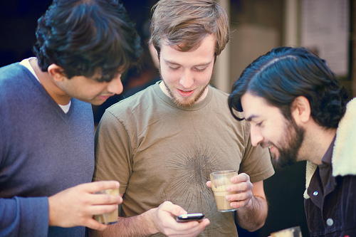 Three guys looking at a smartphone.