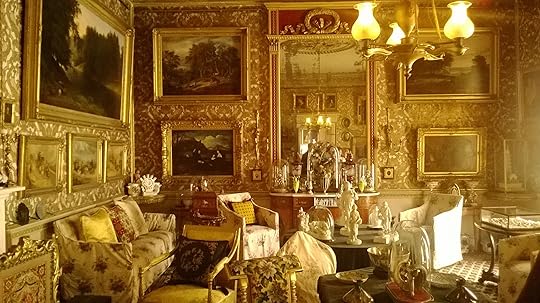 Room crammed with gold-framed paintings and elegant furniture