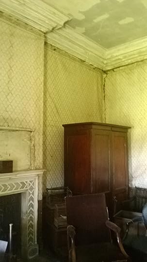 Room with spartan furnishings and damp peeling wallpaper