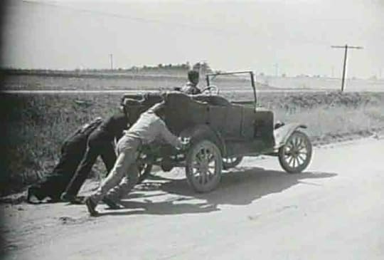 three guys pushing an old car