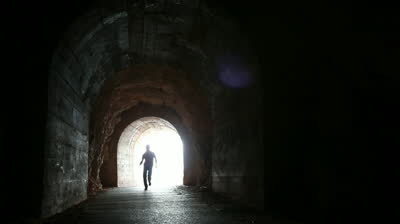 stock-footage-man-runs-into-the-dark-concrete-tunnel-from-the-glowing-end