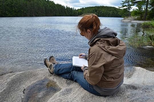 Author Stacey D. Atkinson writing a letter in the woods