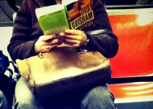 Someone-reading-the-Associate-by-John-Grisham-on-a-train