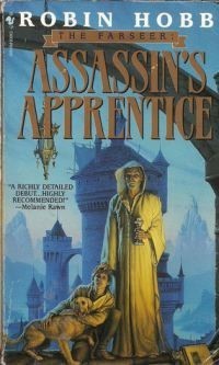 Cover art for Assassin's Apprentice by Robin Hobb, featuring a figure in a hooded white robe standing beside a young white boy holding a dog, with a blue-tinted tower in the background