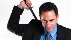 Smiling businessman drawing katana from back