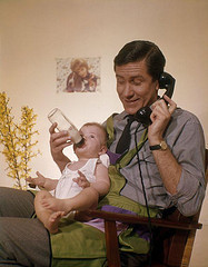 Father on phone feeding baby from Flickr 