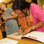 Hari Tiwari autographs a book beside her teacher, Laurie Lalish