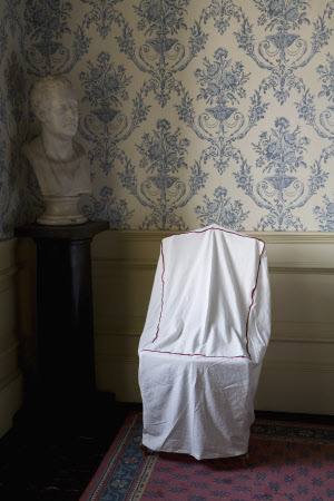 Old bed sheet recycled into a dust cover used on a chair at Petworth House, West Sussex