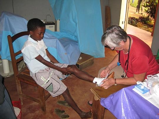 Cass treating a young boy's infected foot. Note how well-dressed and <br />scrubbed the child is. Though poor, families have much pride in presenting <br />themselves and children to the western medical team.