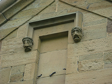 Carved faces, meant to ward off evil spirits. The Celtic masons hired to build the asylum believed evil could only enter through the back, so only the back entrances have these carvings.