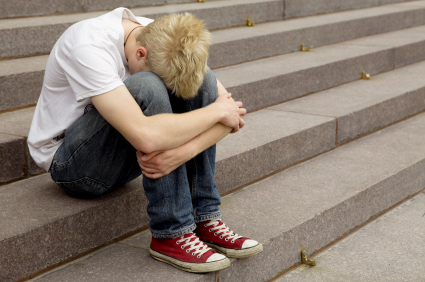 upset young blond man sitting on stairs laying his hand on his arm