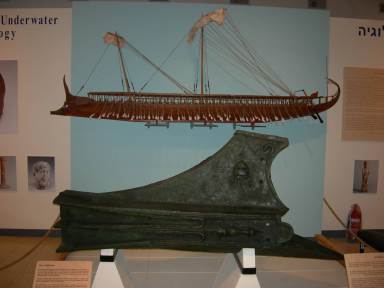 The Athlit Ram on display with a drawing of the warship from which it came behind it. 