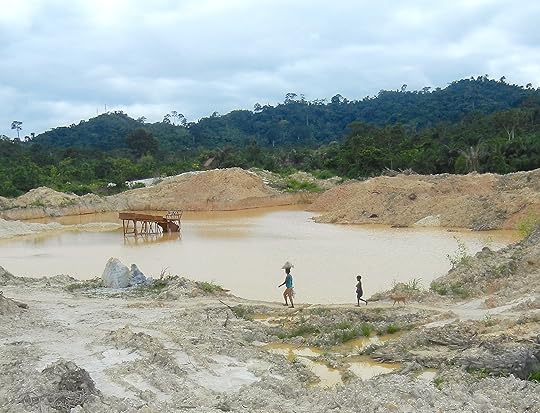 A WOMAN, CHILD AND DOG WALK PAST A PIT MINE