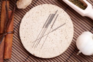 acupuncture needles on a stone plate with herbs