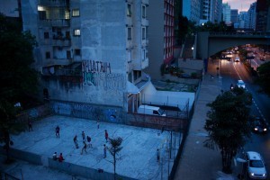 The juxtaposition of the modernized streets with the spontaneous game of pelada embodies the beauty of the street game.