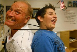 Teacher and student are strangled by large rubberband.