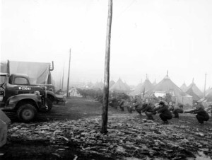 Soldiers who arrived in Anchorage in 1940 had to chop trees and make a space in the wilderness on which to build Fort Richardson. Soldiers can be seen here exercising in front of their tents.