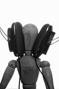 A wooden modeling figure with giant headphones pressed to the sides of its head