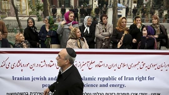 An Iranian Jewish man walks past a banner during a gathering of Iran's Jewish community outside a UN office in Tehran supporting their country's nuclear program, Tuesday, November 19, 2013 (photo credit: AP/Ebrahim Noroozi)