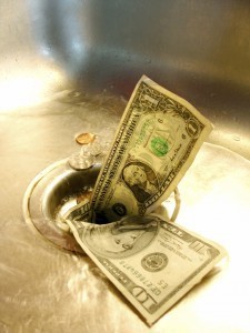 Picture of money going down a drain of a kitchen sink