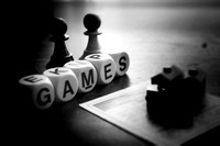 Boggle letters spelling out the word game with Monopoly pieces and chess pawns