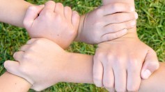Four hands interlocking in solidarity and interdependence