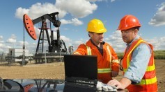 Oil company workers with a laptop in the field