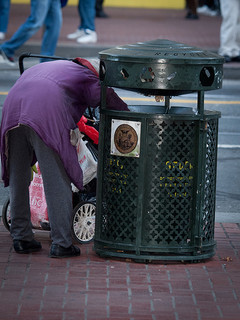 Throw away a book: Homeless woman rummaging through a trash can