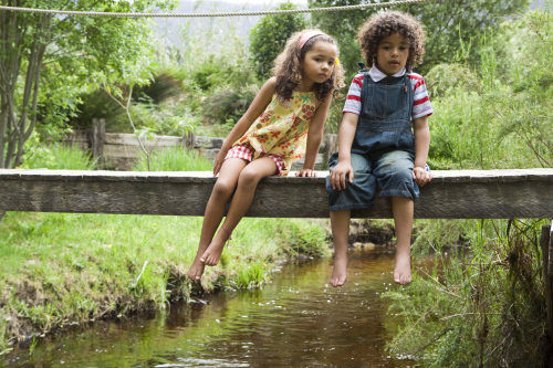 Girl and boy on footbridge over stream