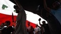 Supporters of Shi'ite cleric Moqtada al-Sadr chant anti-Iraqi government slogans as they march under a giant Iraqi flag during a demonstration calling for the release of detainees held by the Iraqi authorities, in Baghdad's Sadr City (REUTERS/Thaier Al-Sudani). 