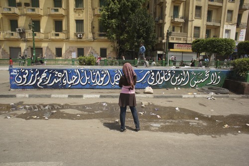 A woman looks at a graffiti of a quote from the Quran, Tahrir Square, <br />November 2011. Photo by Issandr El Amrani.