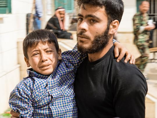 This father is carrying his son to a clinic, the boy has been wounded in the leg by shrapnel. Photograph by Russell Chapman © Copyright 2013