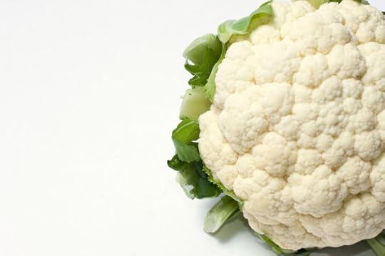 Part of a white cauliflower with leaves on the side