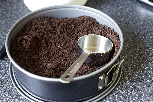 using a measuring cup to press in crumbs