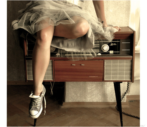 A girl in a skirt and tennie shoes sits on top of a wooden console radio - On the radio by irrr via Deviant Art