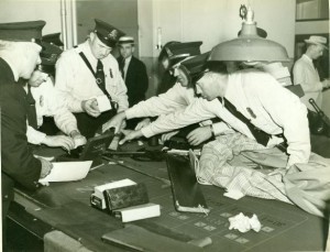Milwaukee police examine evidence from a gambling raid, photo taken in the 1940s.
