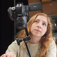 A cheap tripod is better than no tripod; for years I used a $15 Sunpak with no complaints. Some fancier models cantilever over your bench, or if your bench is sturdy you can use a clamp-on articulated arm, like my Manfrotto Magic Arm and Super Clamp.