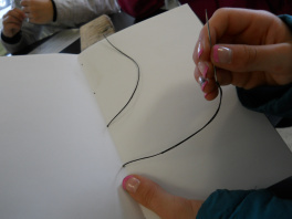 One of the students sewing a book