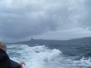 dim outline of an island blurred by seaspray