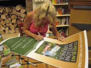 Toni signs posters at a Willow Springs event.
