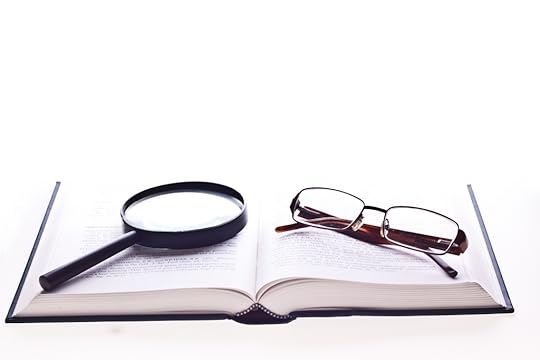 An open book with a magnifying glass and a pair of reading glasses.