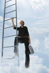 Mixed race woman climbing ladder in clouds