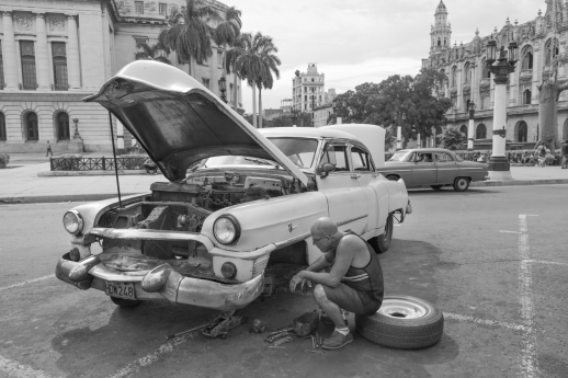 Broken Down Car with Owner Trying to Change the Tire