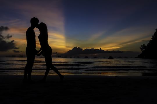 silhouettes of young loving couple kissing on tropical beach