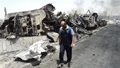 REUTERS - A man walks past near remains of burnt vehicles belonging to Iraqi security forces in the northern Iraq city of Mosul, June 13, 2014.