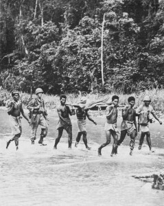 Native litter bearers evacuate an American casualty across the Driniumor River in New Guinea, 1944. (US Center of Military History)