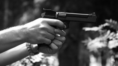 A gun in a man's hand on a dark background
