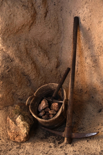 Ancient mining tools and basket full of rocks inside a tunnel in a mine